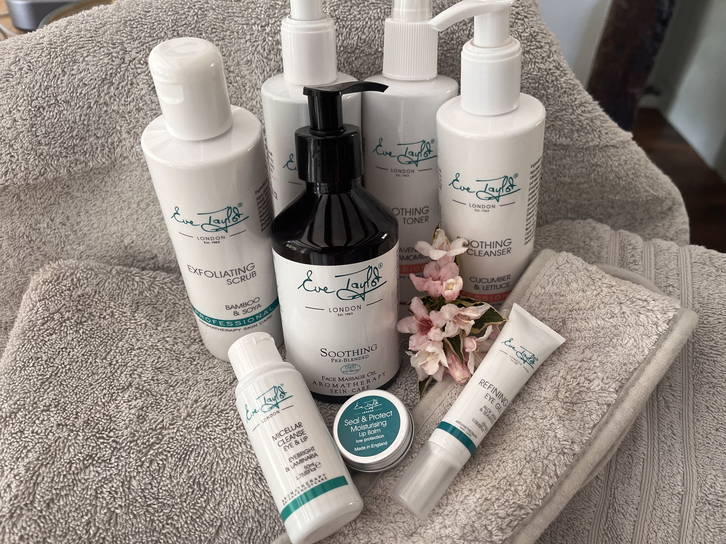 Collection of skincare and beauty products including cleansers, toners, moisturizers, and lip balm with white bottles and black pump.