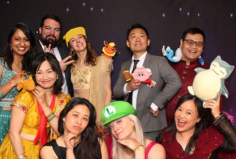 Ten people posing for a photo, some holding plush toys, in front of a dark background with stars.