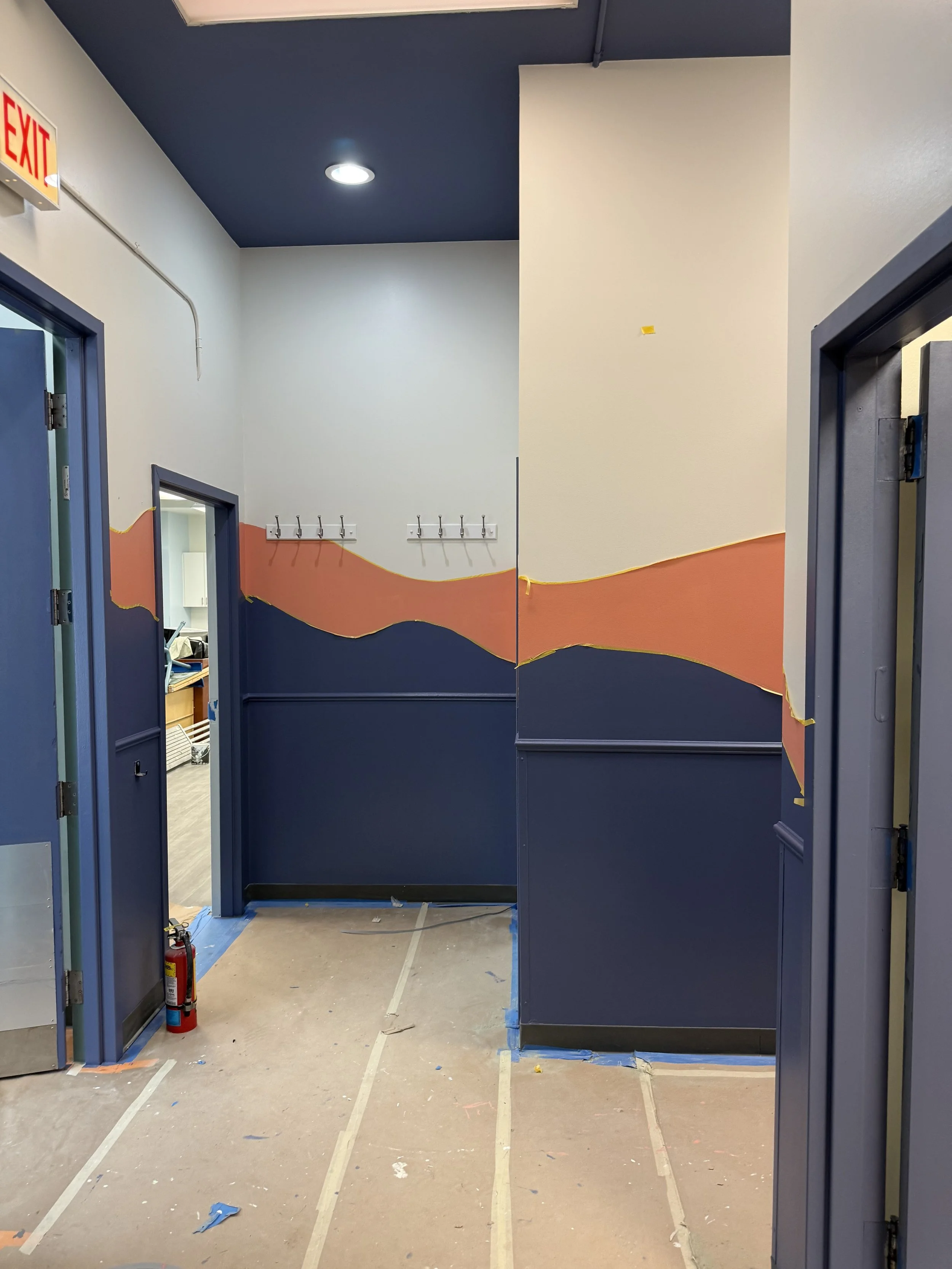 Interior view of a building under construction, showing metal framing, door openings, and a curved concrete floor.