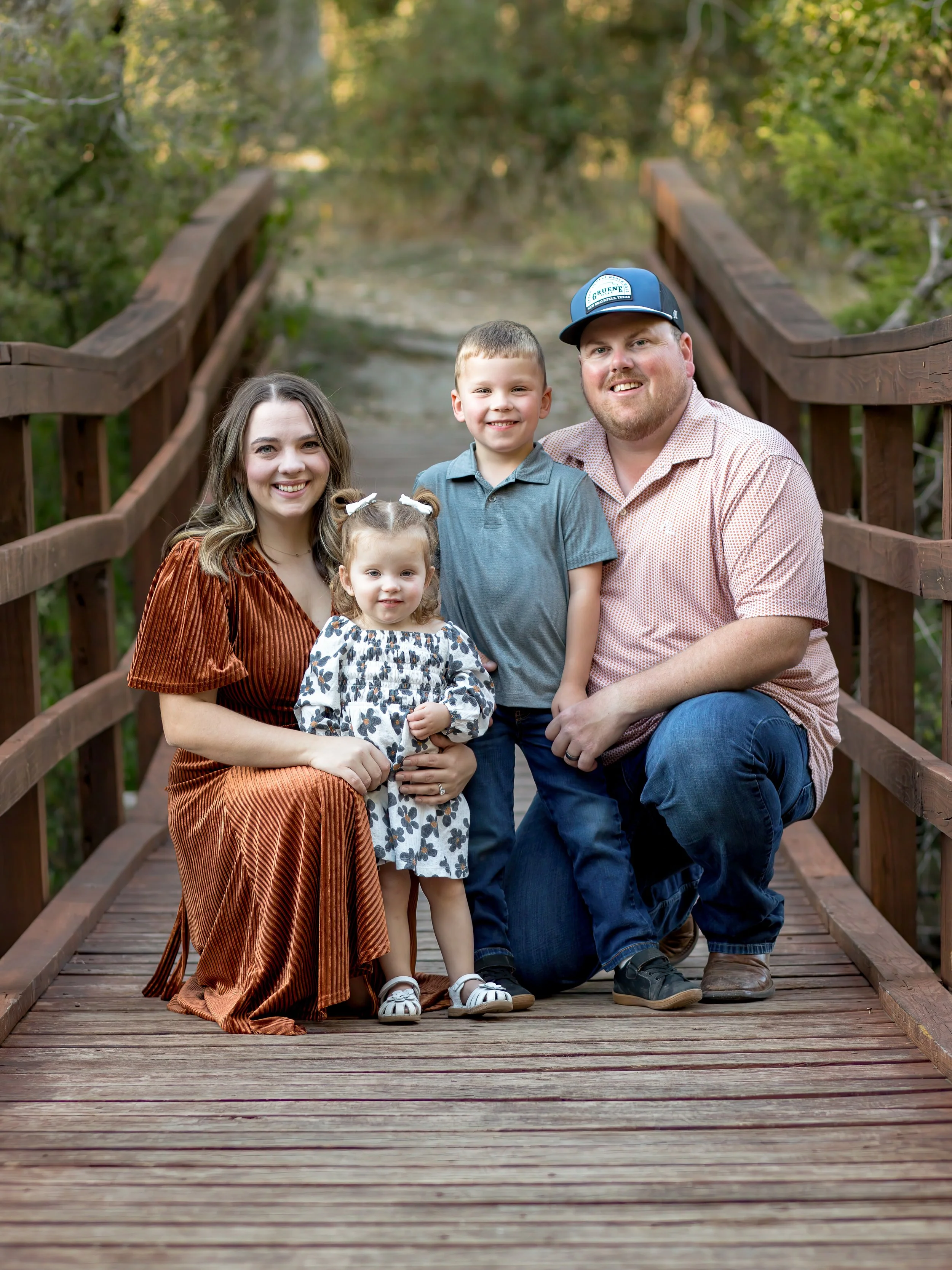 Family of four on a bridge smiling. They are the owners of Platinum Irrigation and Scapes, a family run landscaping business in New Braunfels TX