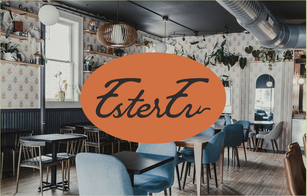 The restaurant features patterned wallpaper, decorative shelves, blue upholstered chairs, and light wooden tables. Its modern industrial design includes exposed ductwork, hanging lights, and a large orange 'EsterEv' logo overlay.