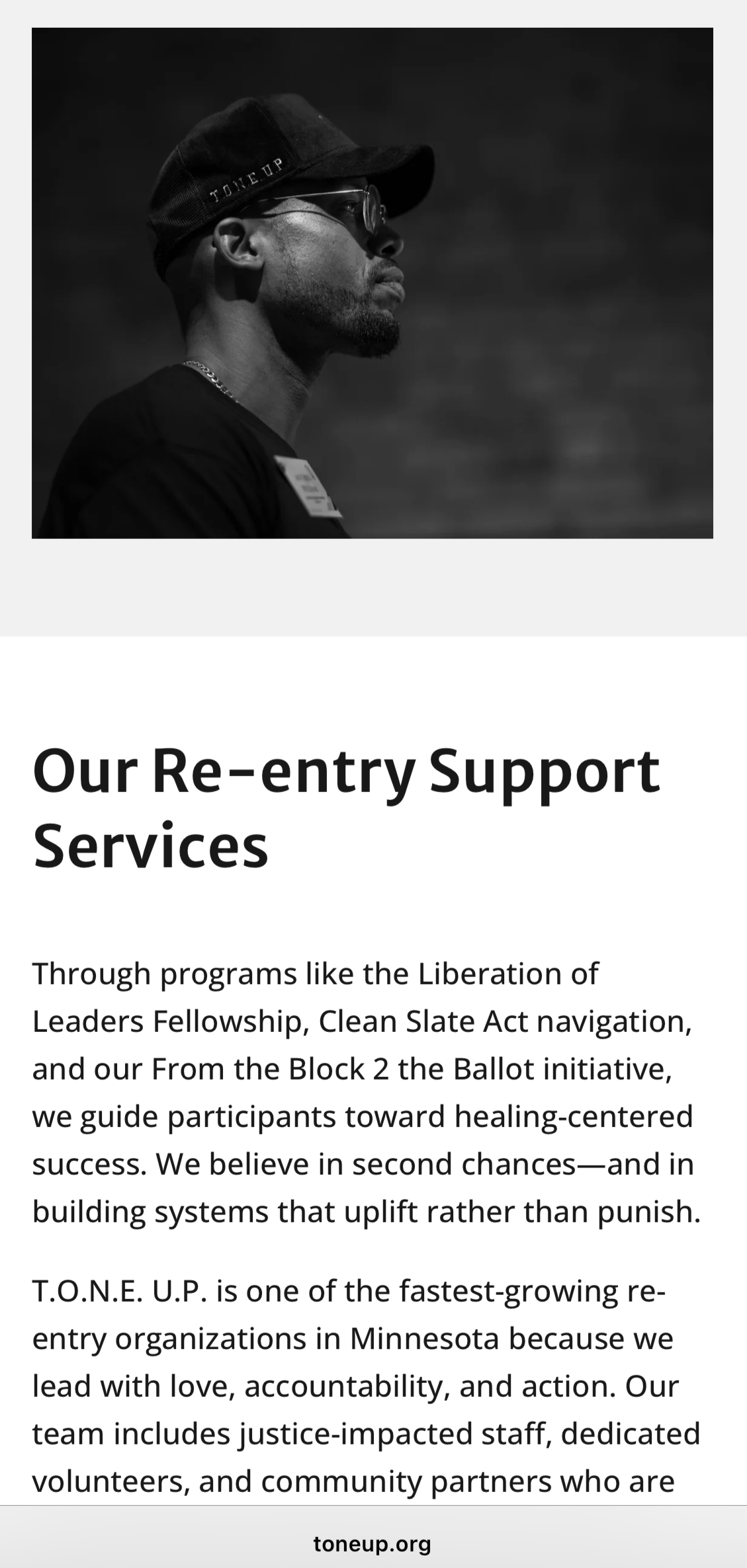 A black and white profile portrait of a man wearing a cap, sunglasses, and a shirt, with a blurred background.