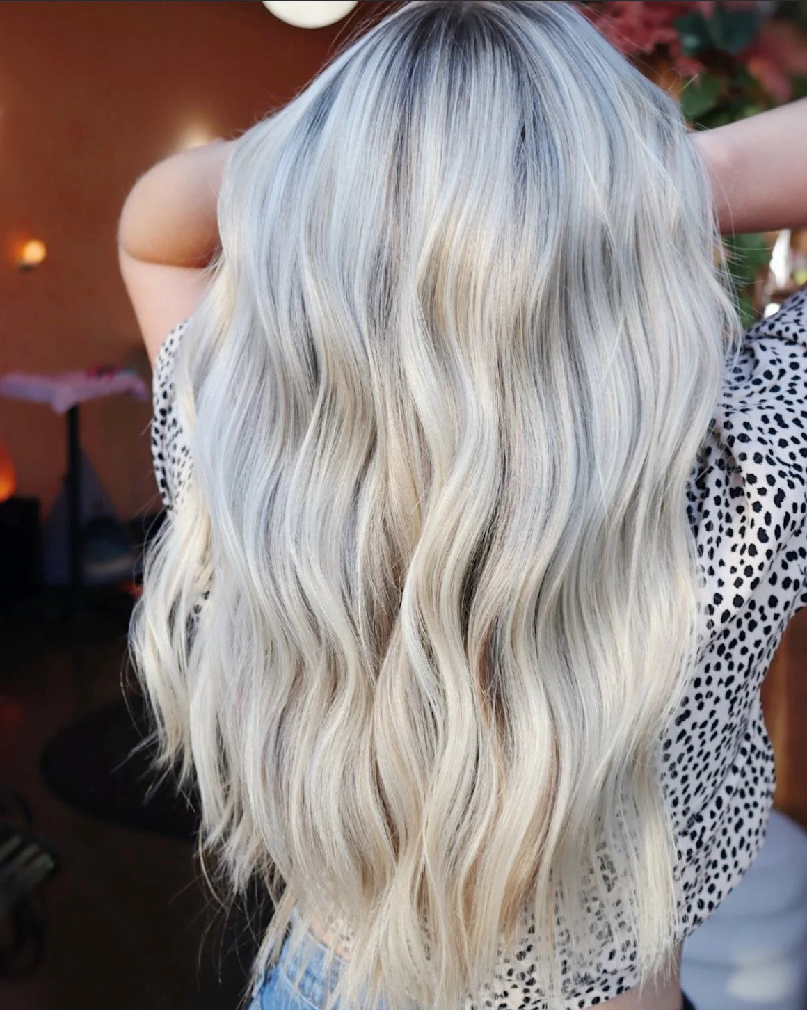 Person with long, wavy, platinum blonde hair, wearing a polka-dotted shirt.