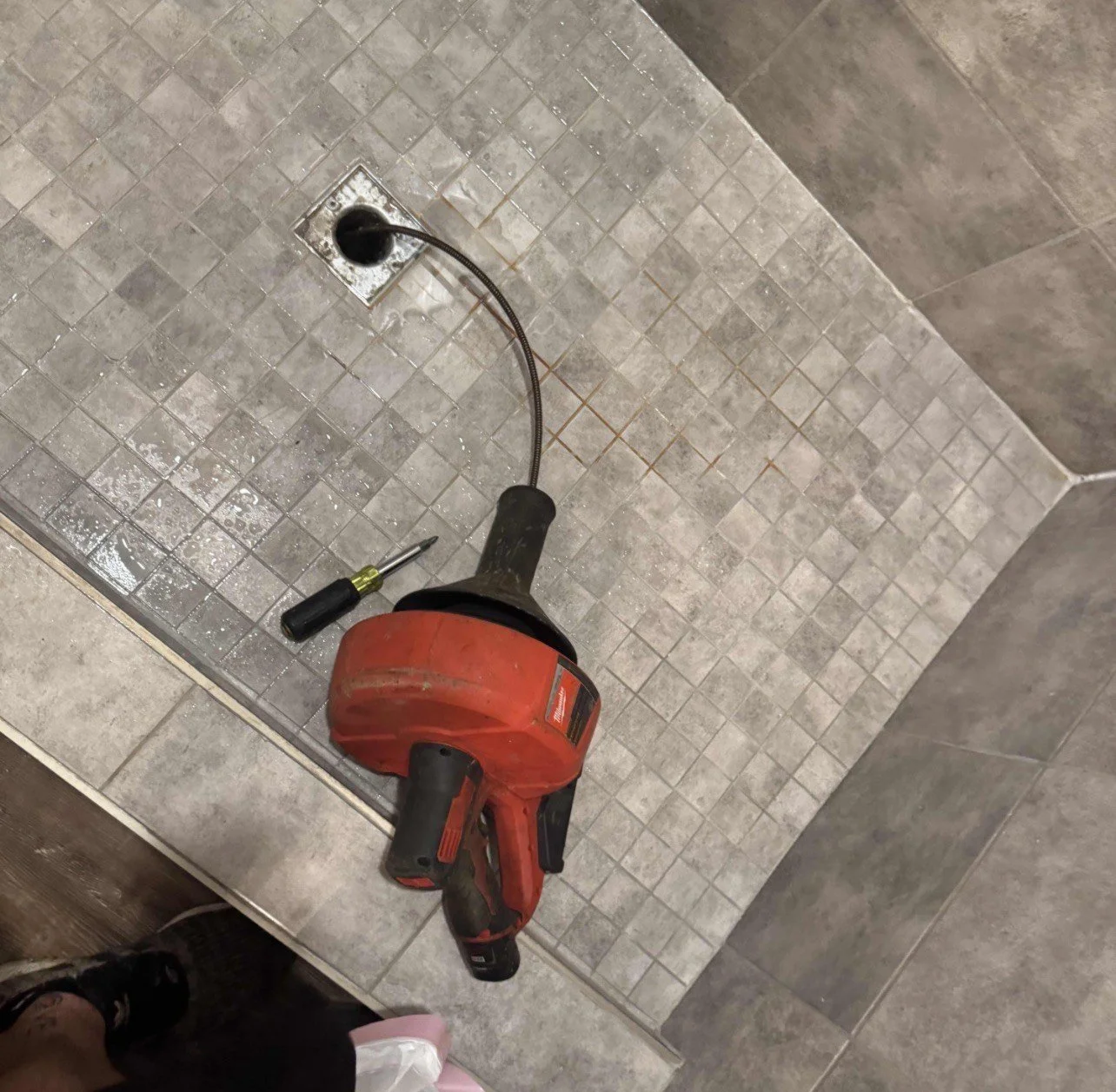 Professional plumber using drain snake to clear blocked pipe.