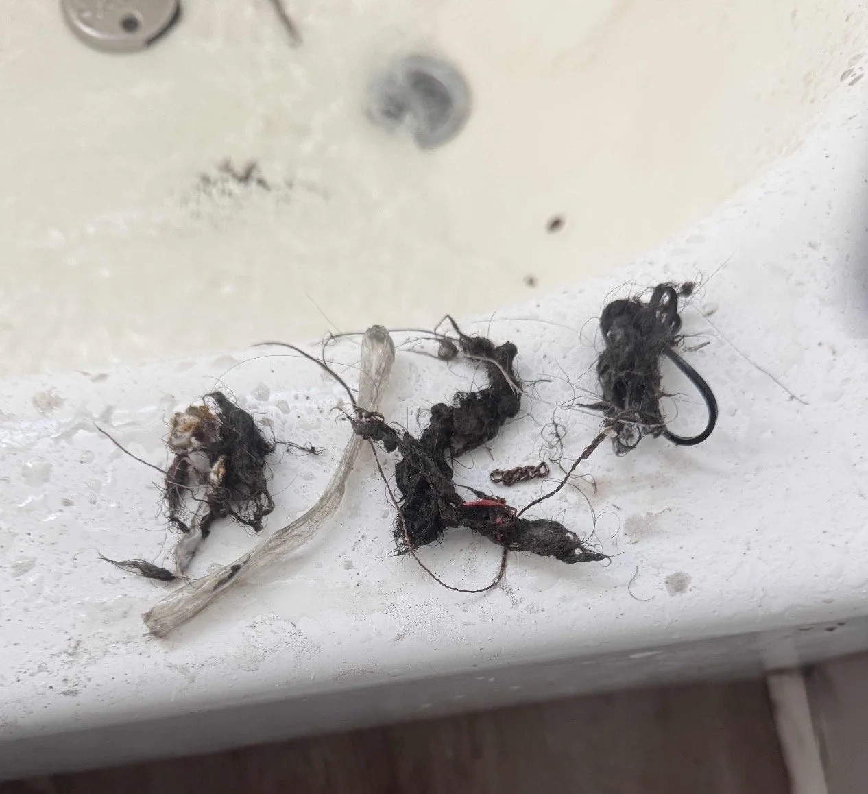 Clogged drain repair removing hair buildup in residential bathroom