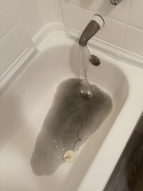 Professional plumber using drain snake to clear blocked pipe.