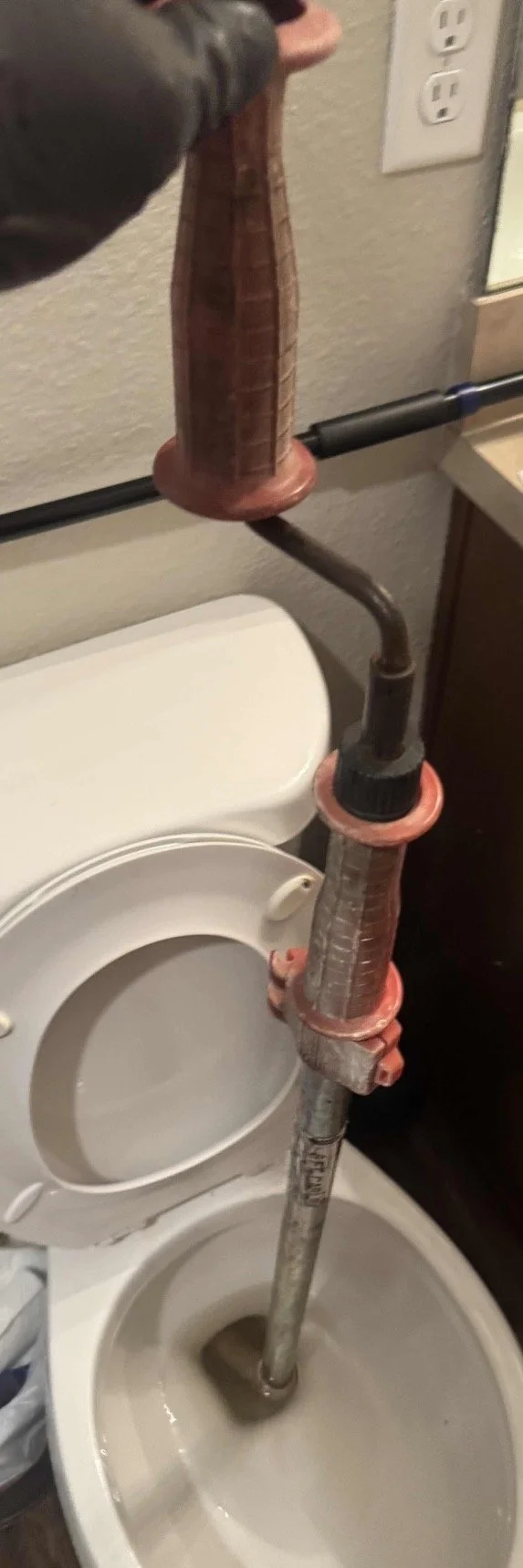 Using a professional-grade closet auger to clear a stubborn toilet blockage in a Jacksonville residential bathroom.