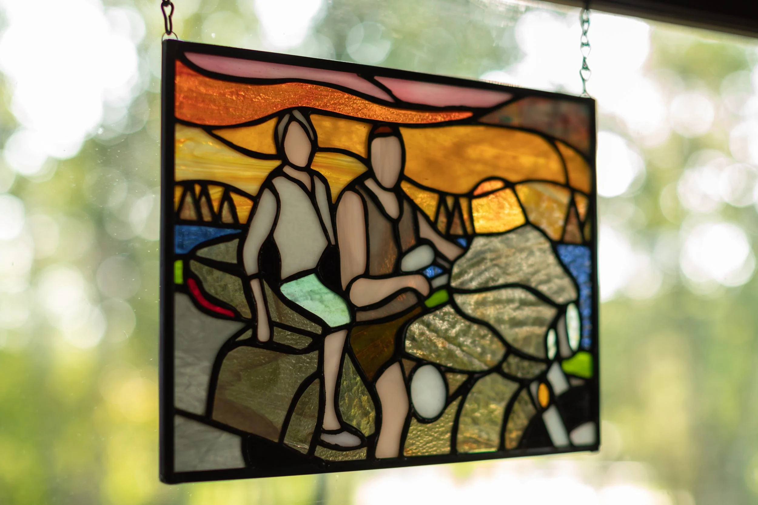 Stained glass motorcycle panel during sunset with trees in the background.