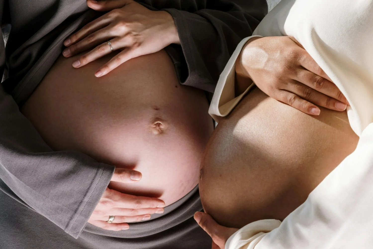 two women holding their own pregnant bellies