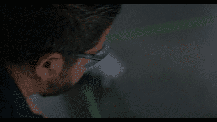 Close-up of a man's face from the side, wearing glasses, with a dark background.