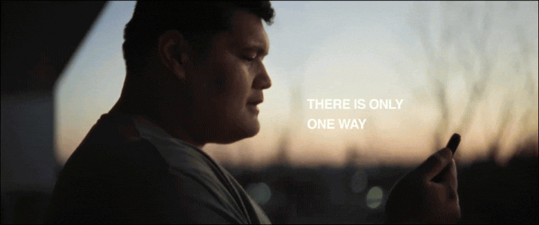 A man is looking at his phone in a car during sunset.