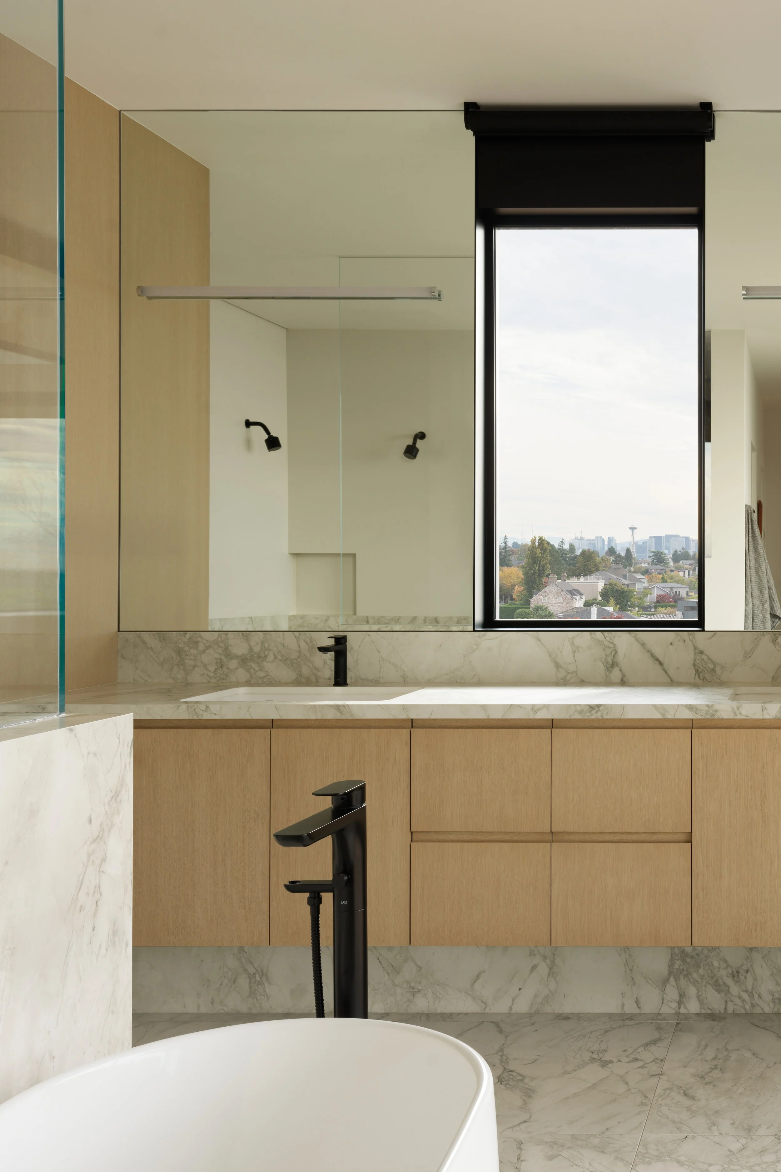 Primary Bathroom with soaking tub, white oak cabinets, and white marble floors and countertops