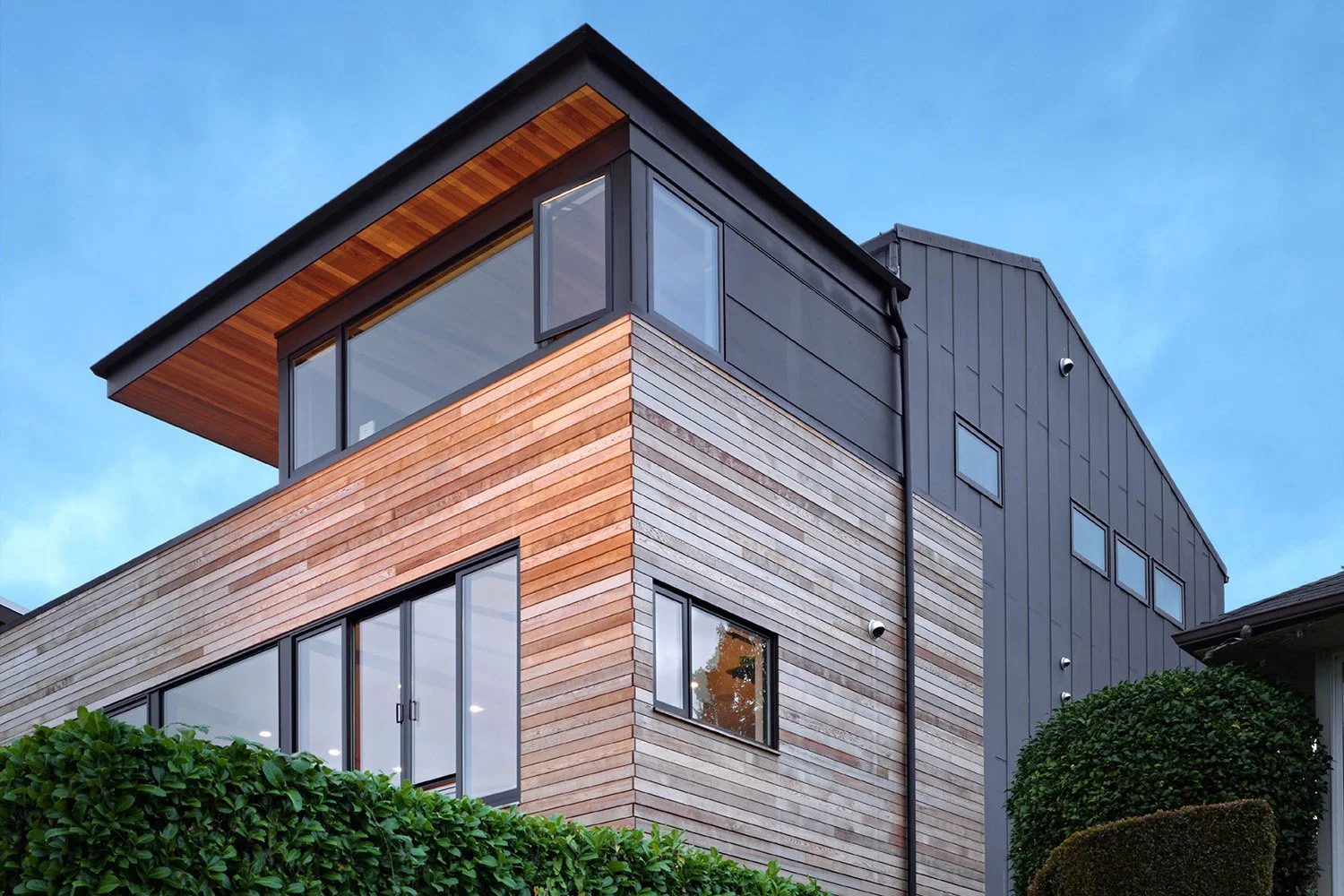 Warm modern residence with combination of siding materials and roof forms