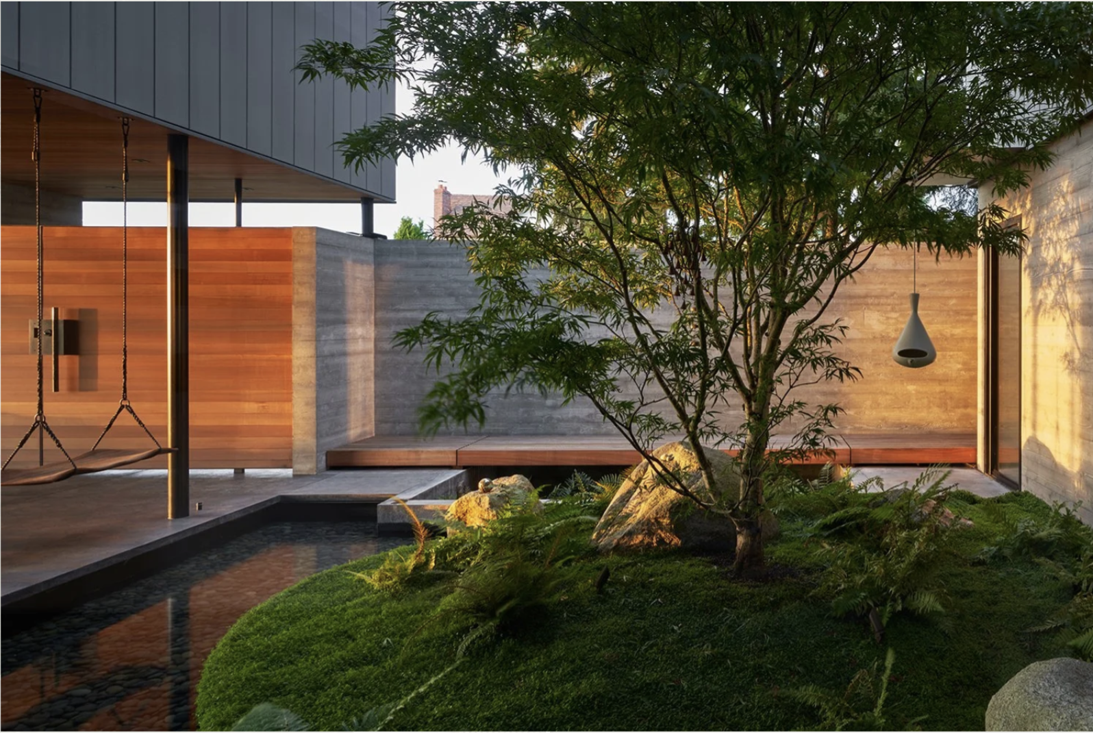 A lush central courtyard with a water feature, floating swings, and fire pit.
