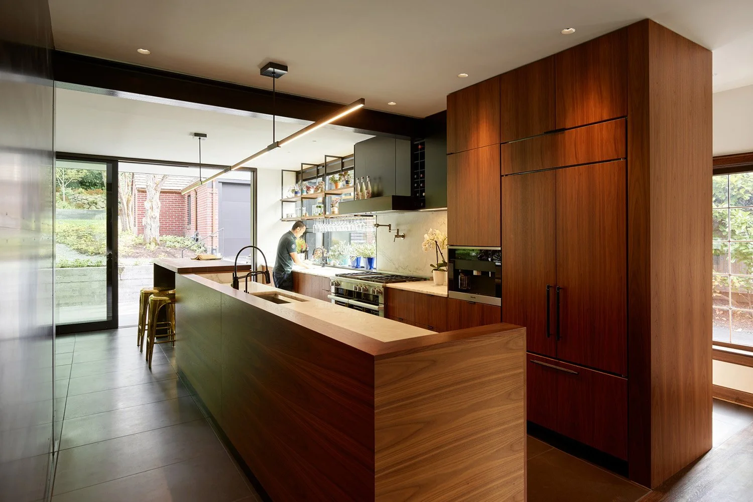 Modern walnut Kitchen with long island with wood linear light and basalt flooring