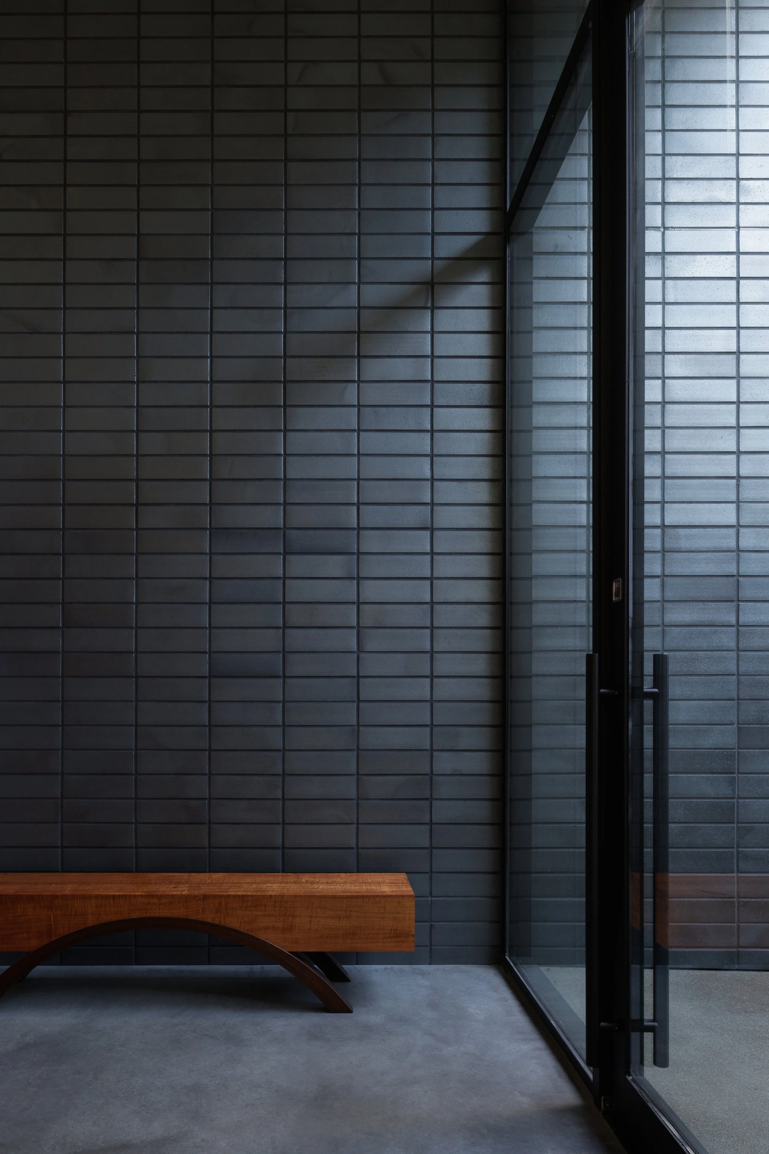 Entry with koa wood bench and indoor outdoor black brick