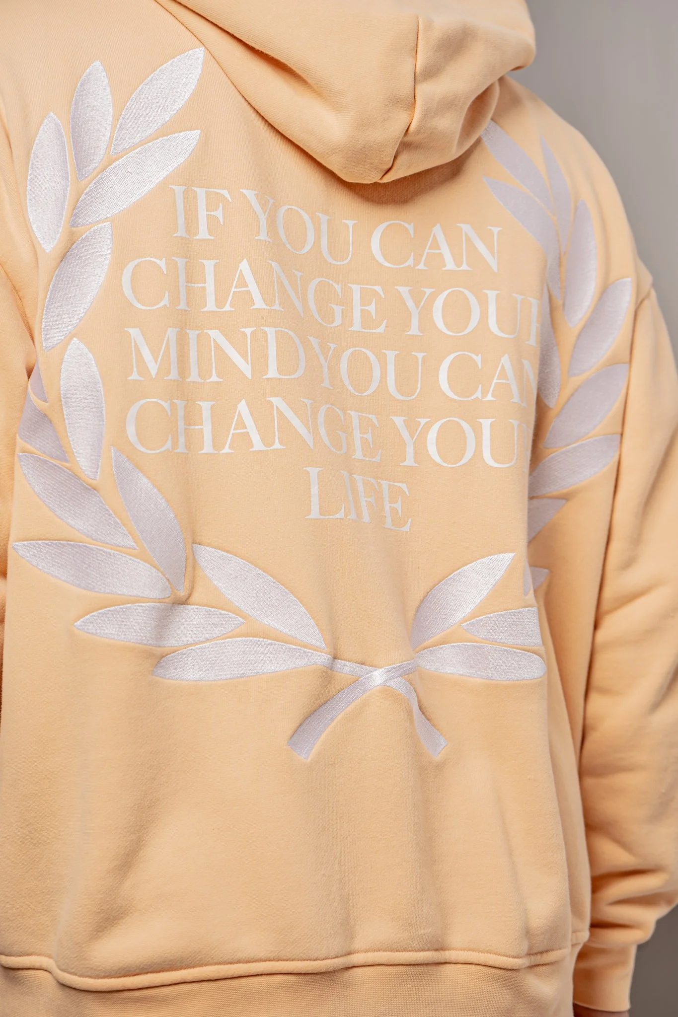 Peach-colored hoodie with white text and a leaf design. The text reads, "IF YOU CAN CHANGE YOUR MIND YOU CAN CHANGE YOUR LIFE."