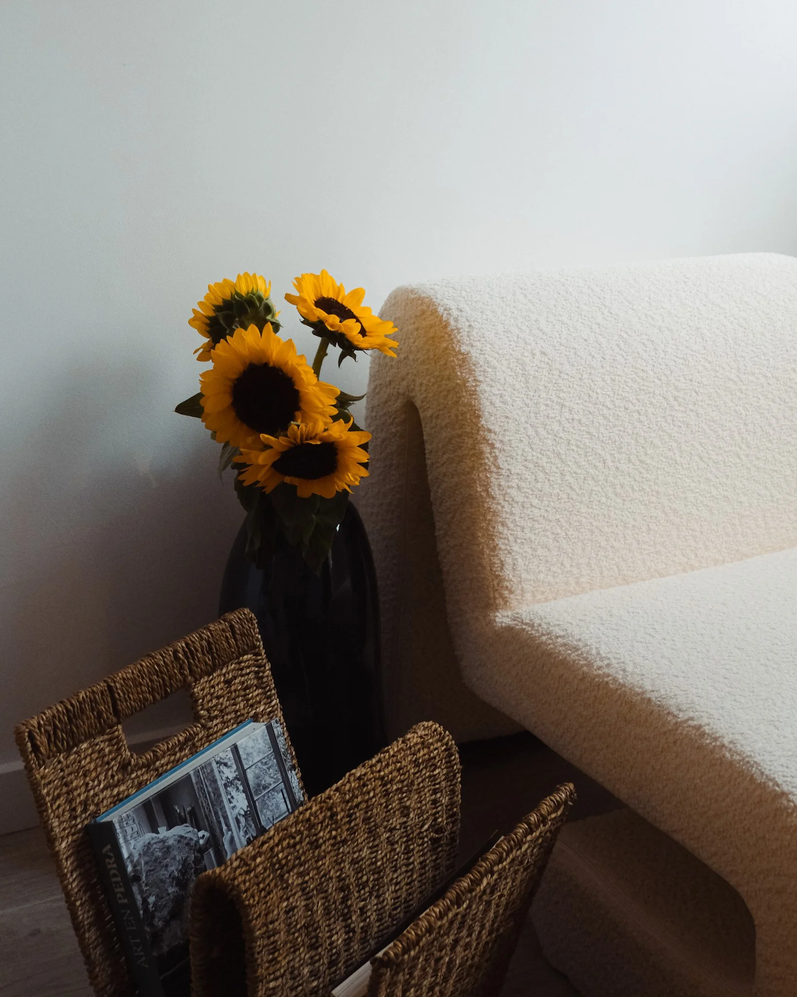 Ramo de girasoles en una mesa junto a un sillón y una revista.