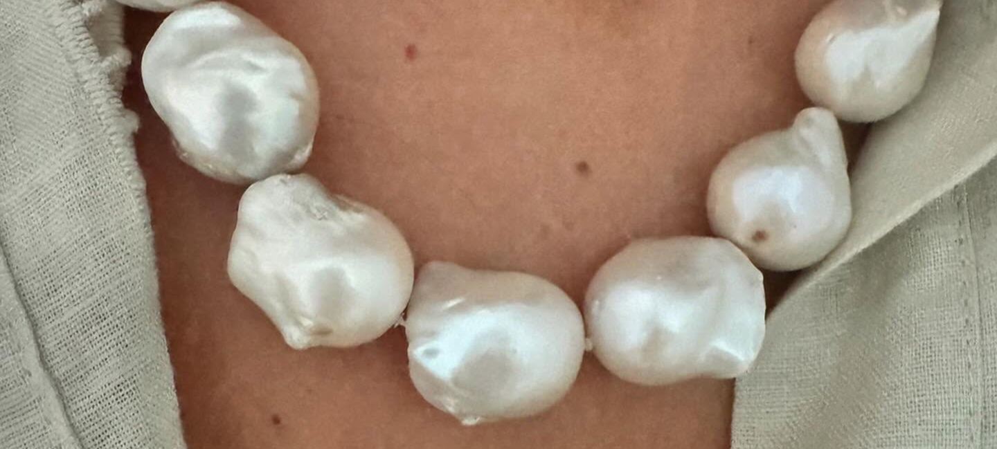 Persona con una gargantilla de grandes perlas blancas