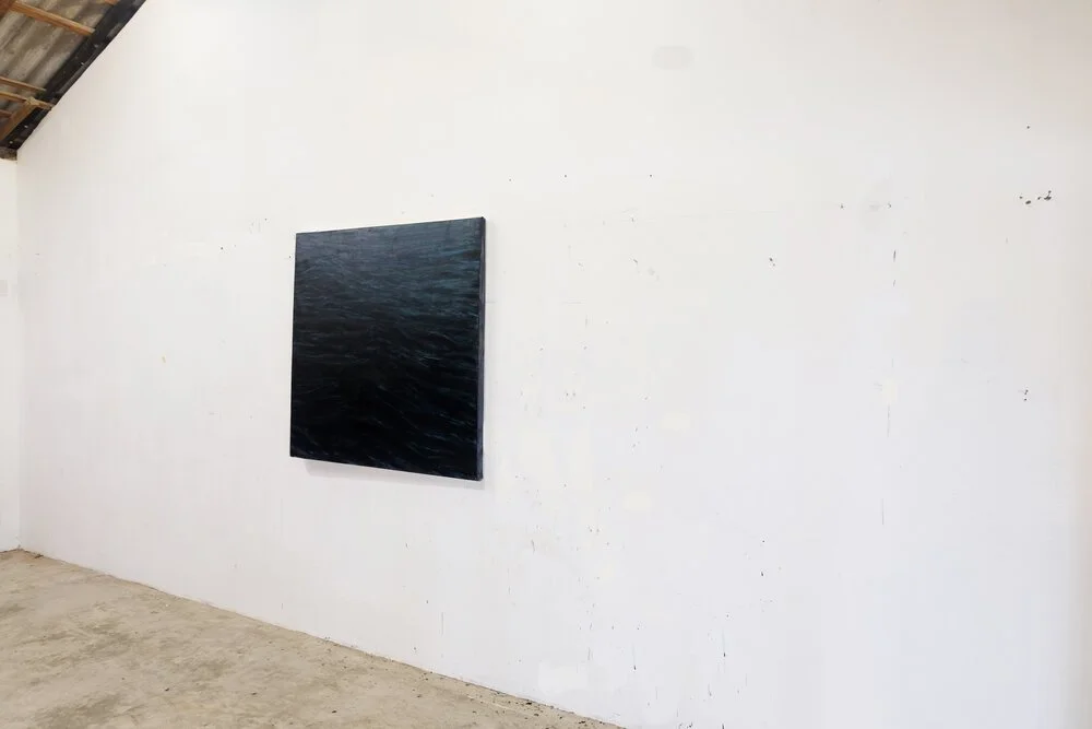 Cuadro abstracto en tonos oscuros colgado en una pared blanca en una galería