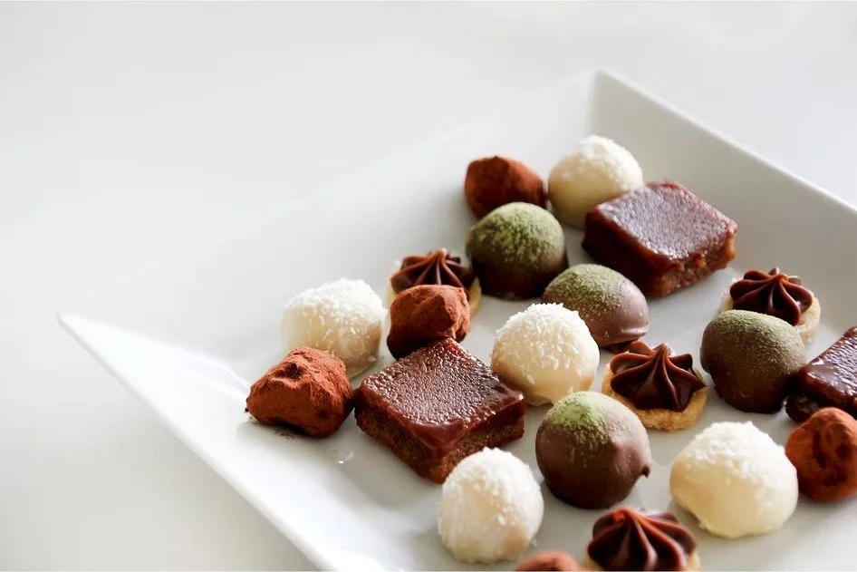 Una variedad de bombones y chocolates decorativos en un plato blanco.