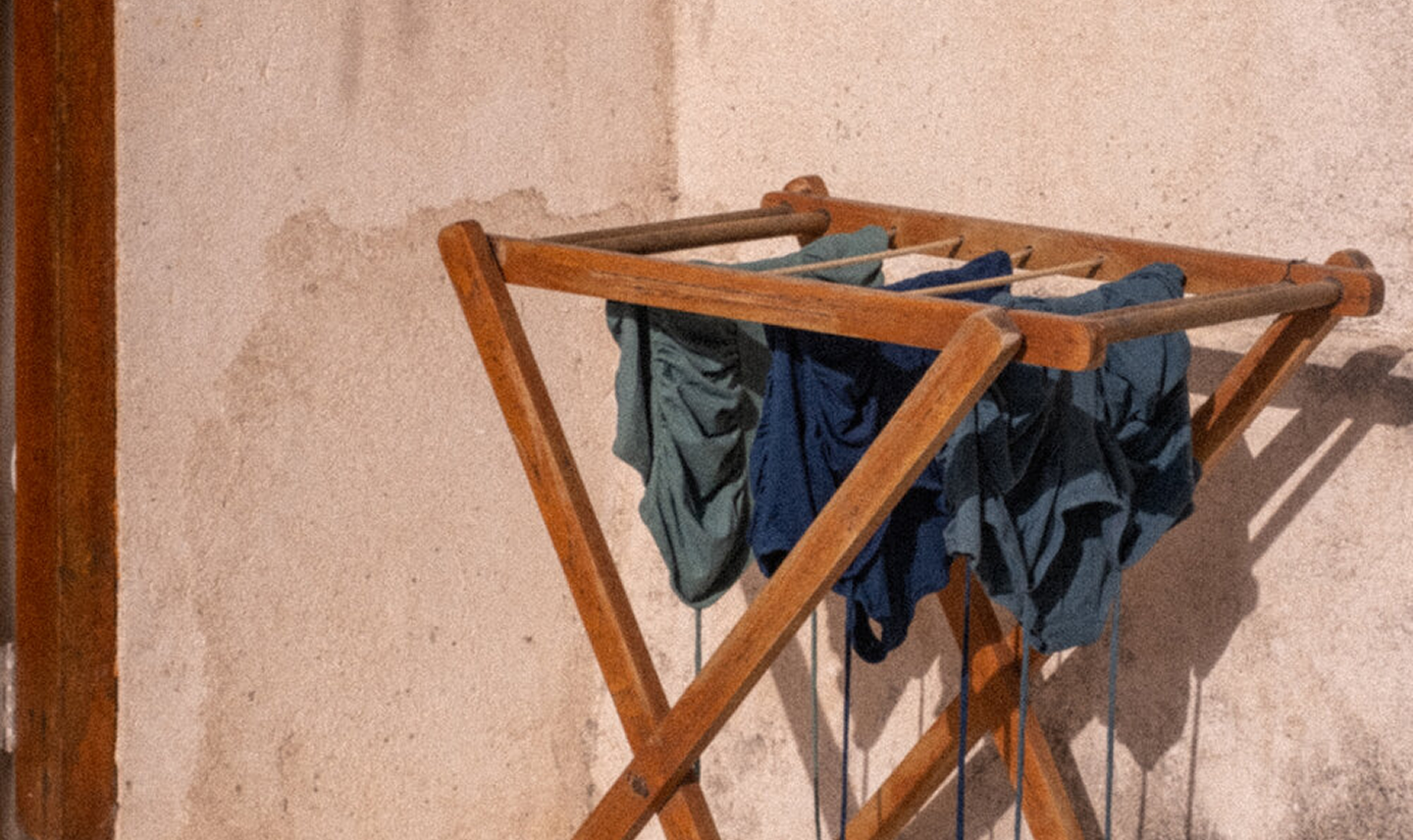Pantalos de ropa colgados en un tendedero de madera, en una pared con textura