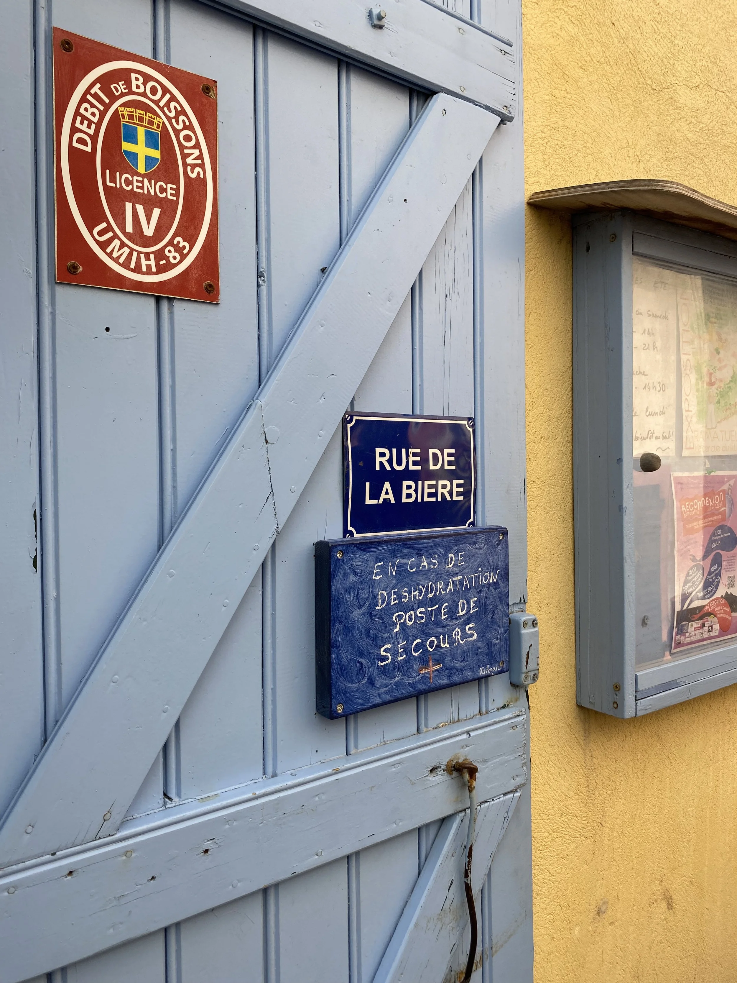 Puerta de color azul con señales, una de ellas indica 'Rue de la Bière'. Otra señal pequeña dice 'En caso de deshidratación, poste de secours'.