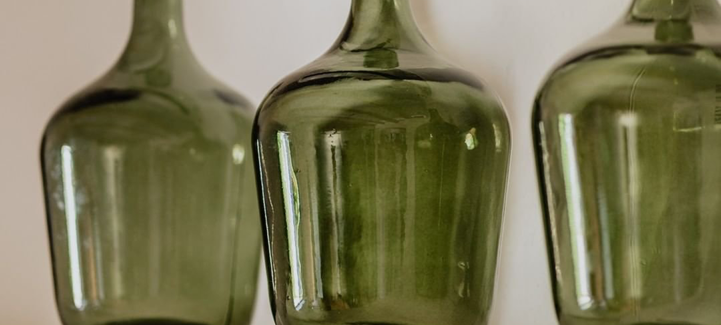 Tres botellas de vidrio verde, sin etiquetas, en línea recta.