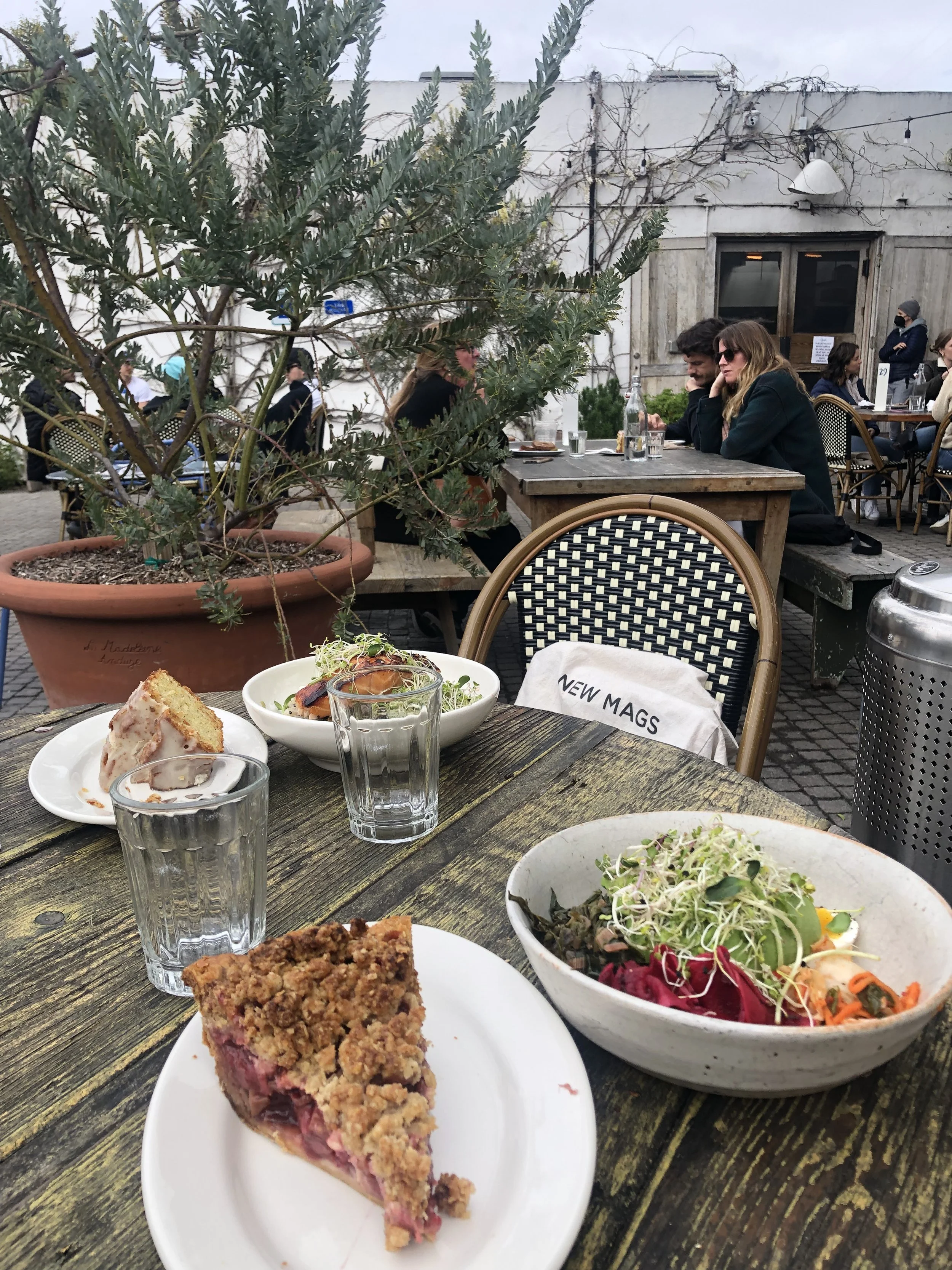 Table with slices of cake, salad, water and food in an outdoor restaurant.