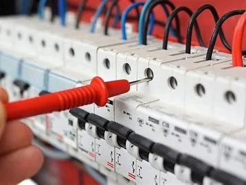 Close-up of a hand using a screwdriver to work on electrical circuit breakers with wires connected.