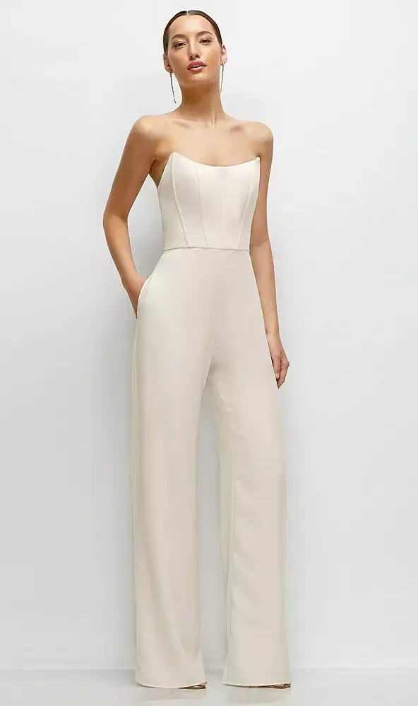 Woman in a strapless cream-colored jumpsuit with wide-leg pants, standing against a plain white background.