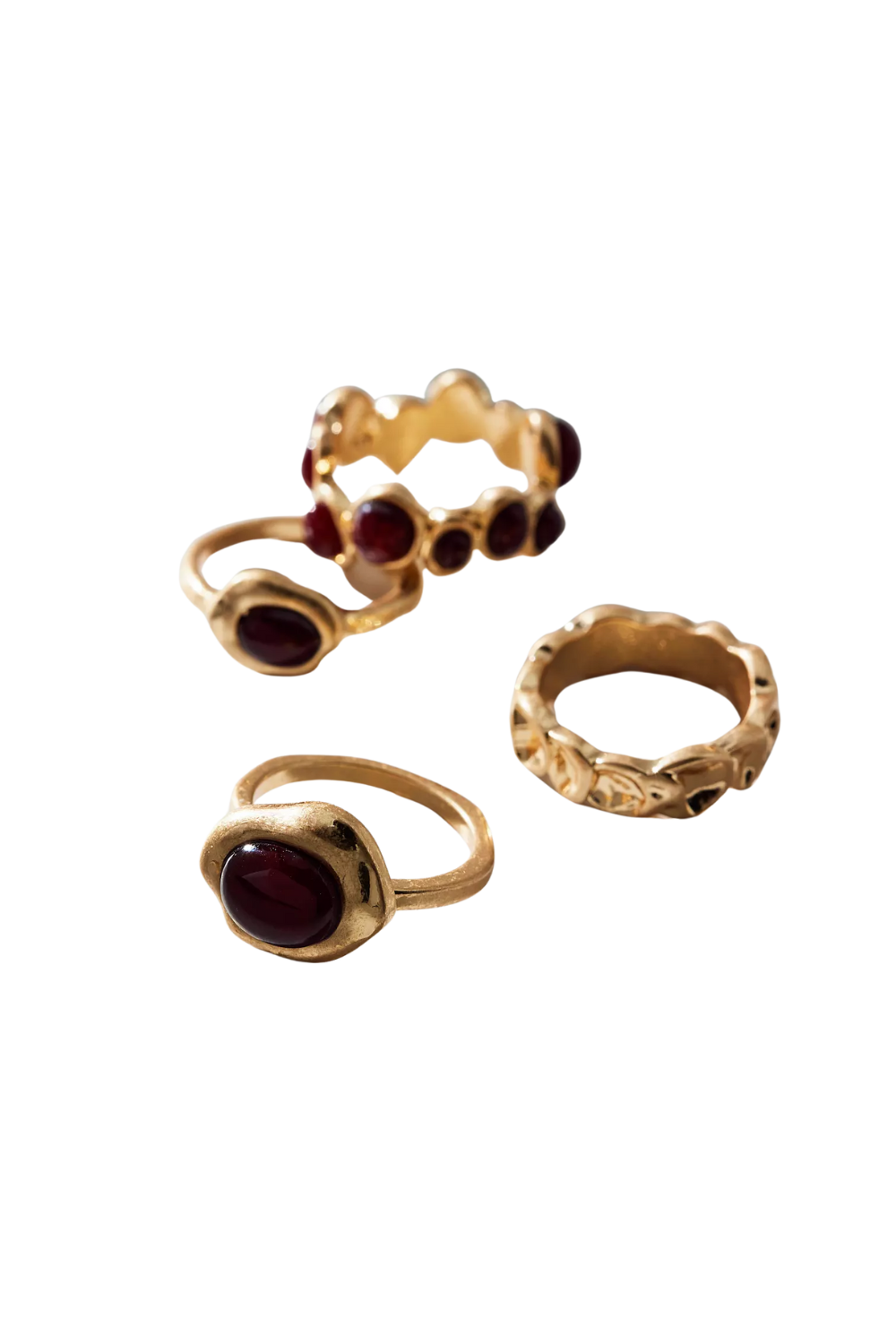 Close-up of four gold rings with dark red gemstones, different designs, arranged on a black background.