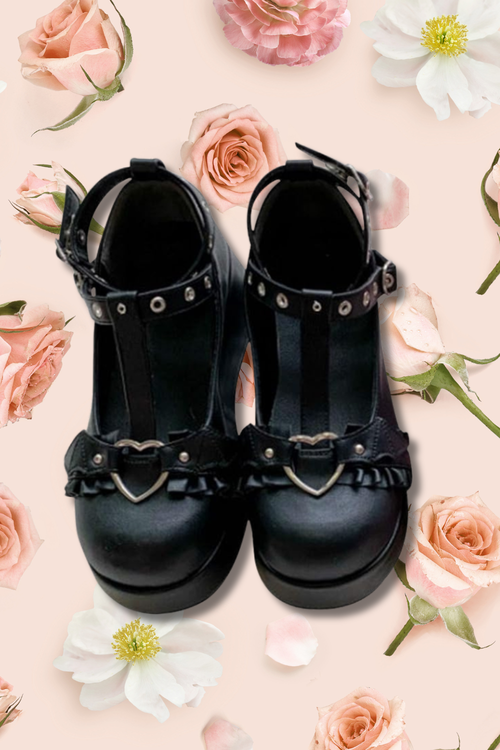 Black pair of high-heeled shoes with straps and metal accents on a light pink background with scattered roses and flower petals.