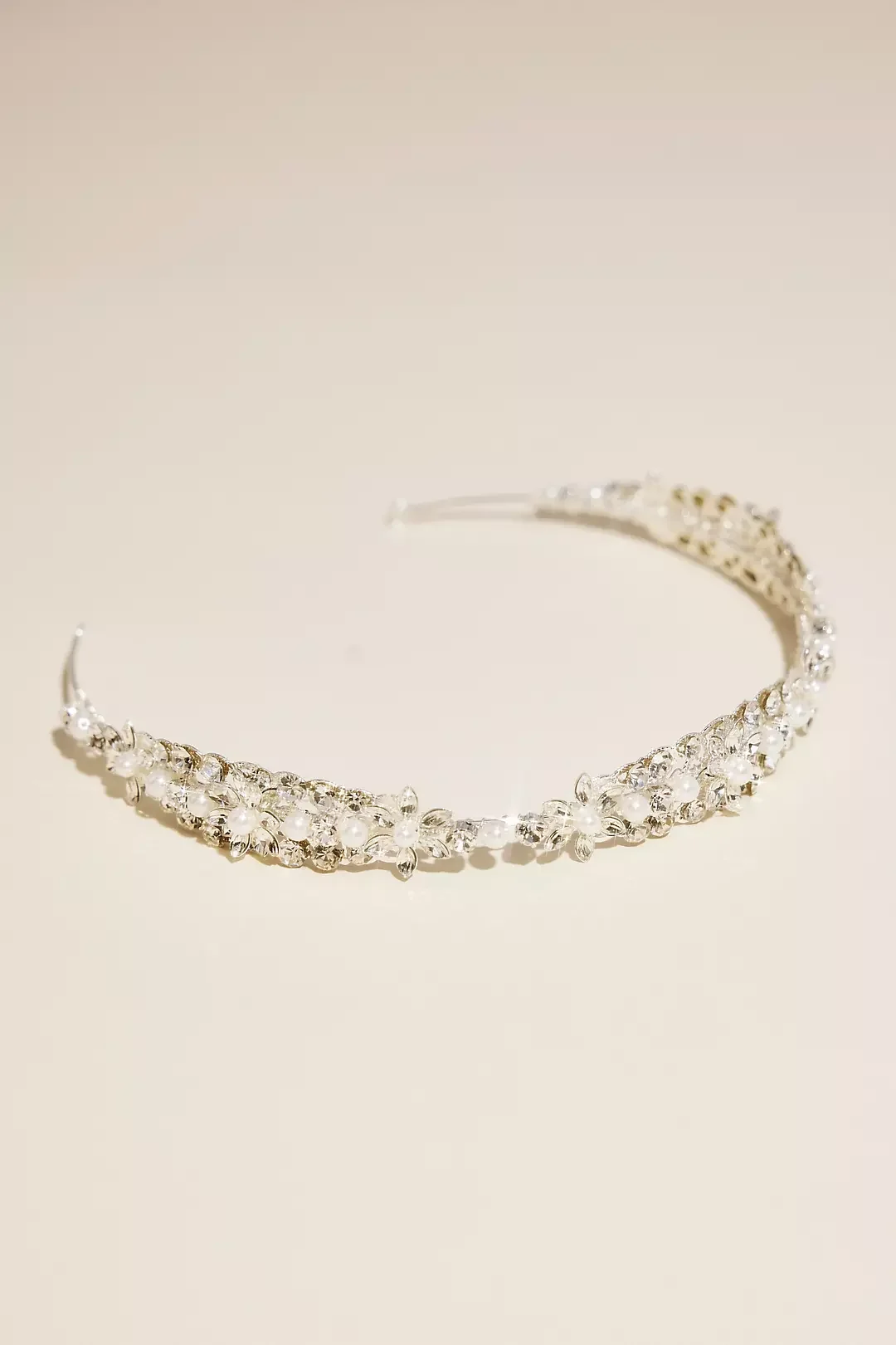 A silver tiara with pearls and gemstones on a plain light background.