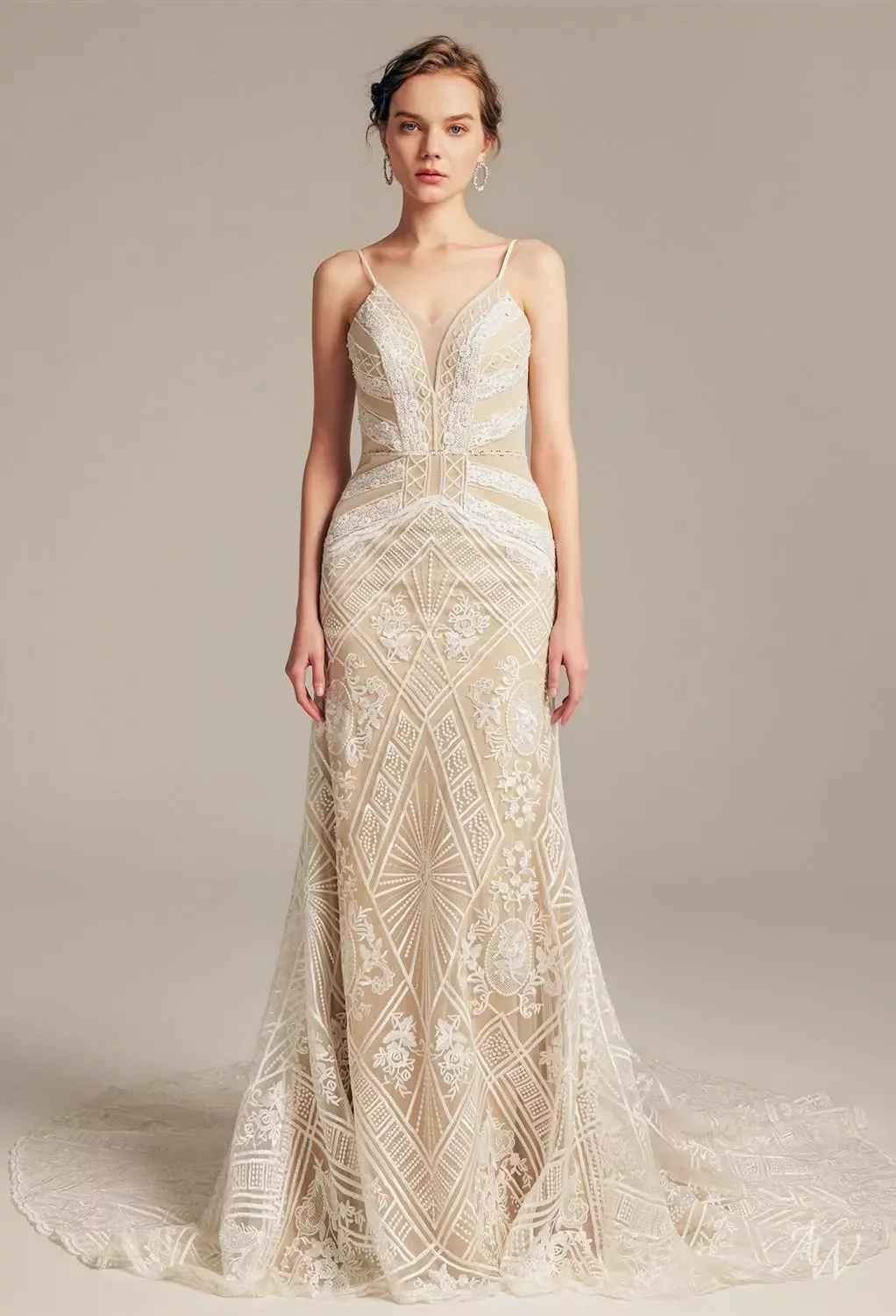 A woman wearing a beige, intricately embroidered, sleeveless, floor-length gown with thin straps, against a neutral background.
