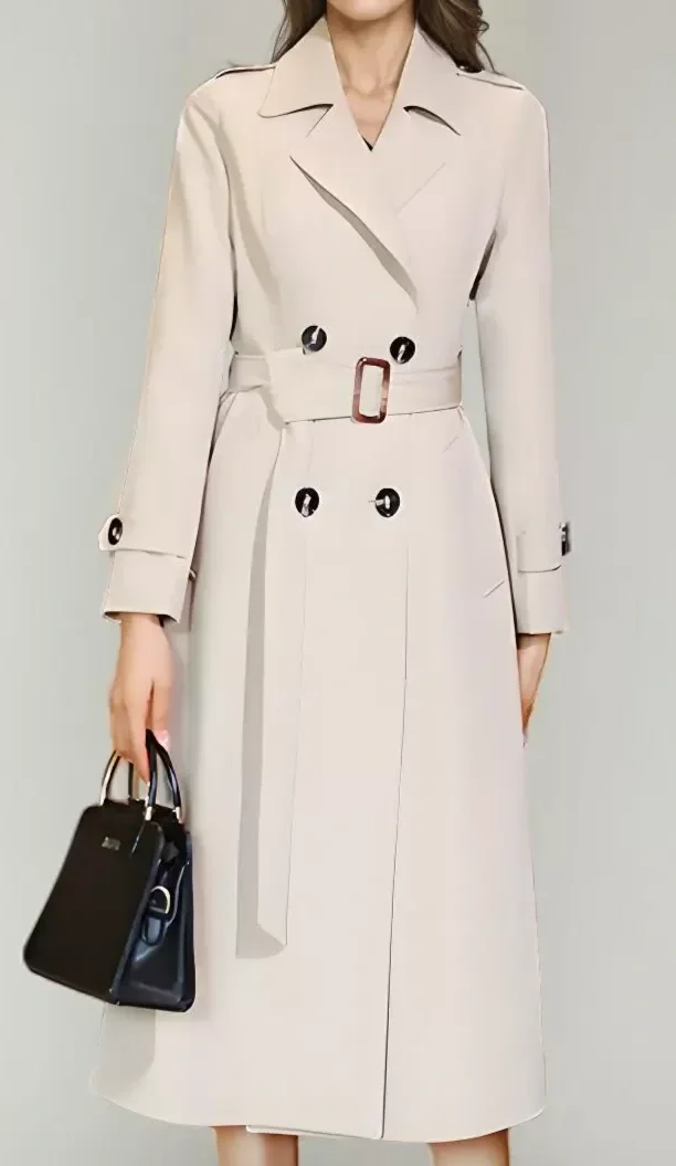 A woman wearing a beige trench coat holding a black handbag.