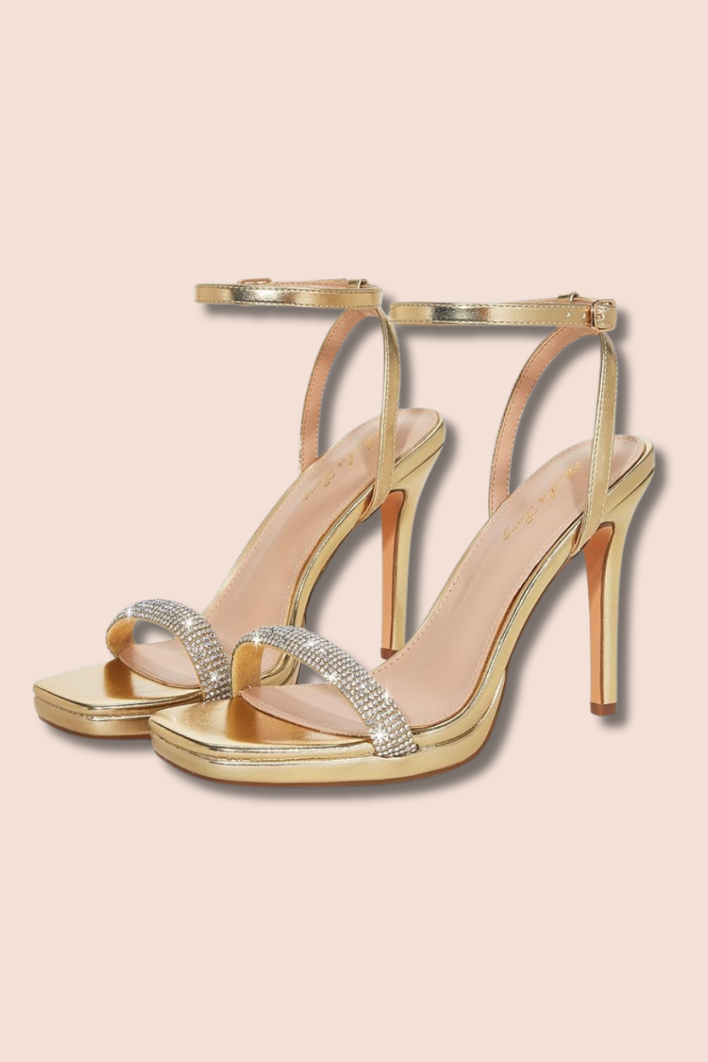 Gold high-heeled sandal shoes with rhinestone embellishments on the straps, set against a light pink background. everyday wear, cute outfit, night on the town, heels, womens attire