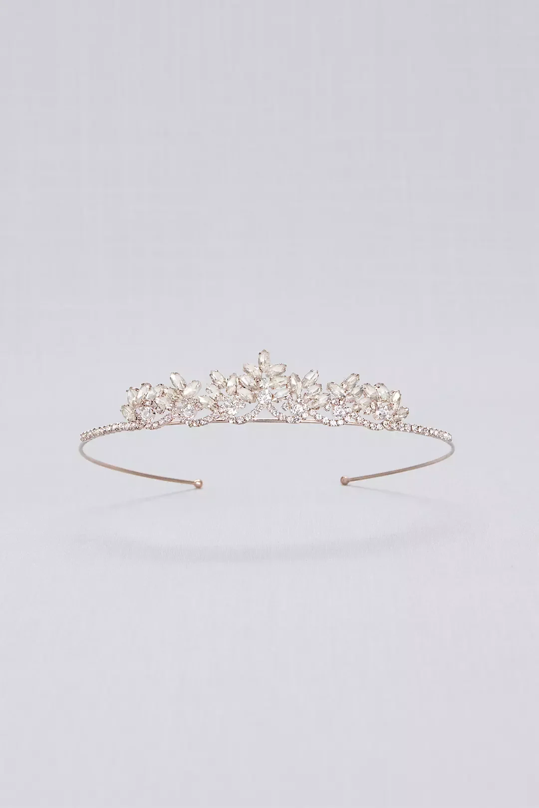A silver tiara with floral design and clear gemstones on a plain light grey background.