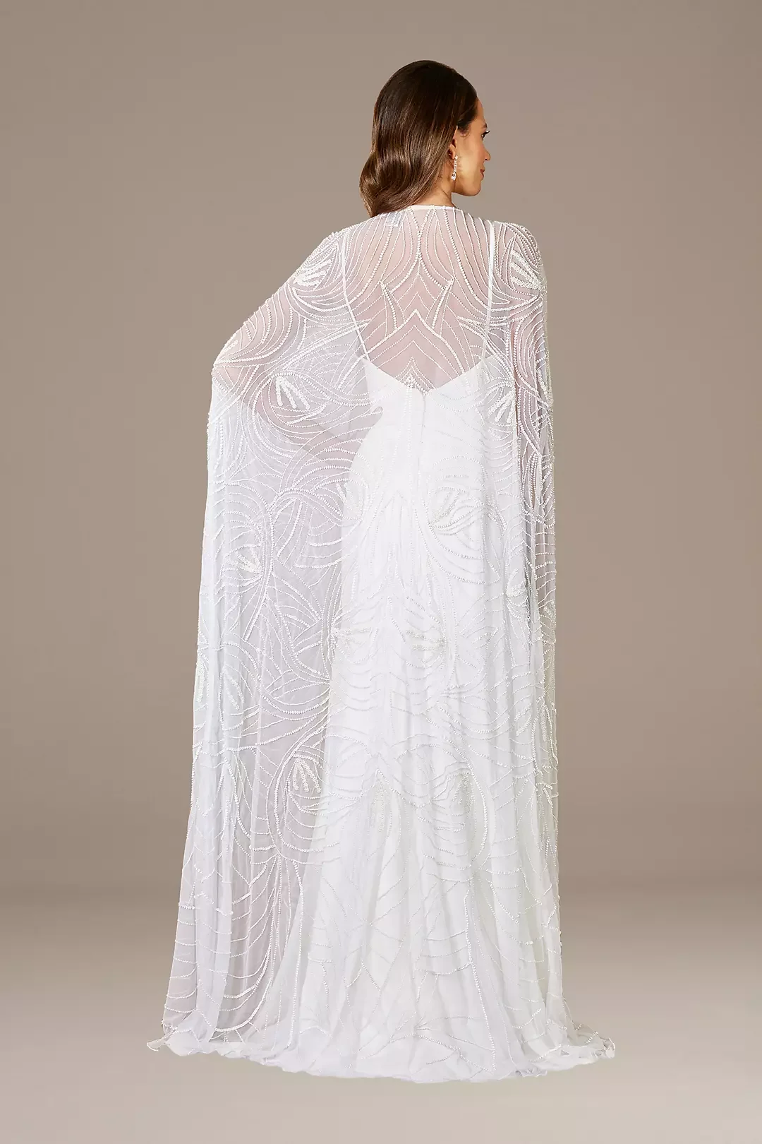 Elegant white dress with intricate beaded embroidery, modeled by a woman with long brown hair, viewed from the back against a neutral background.