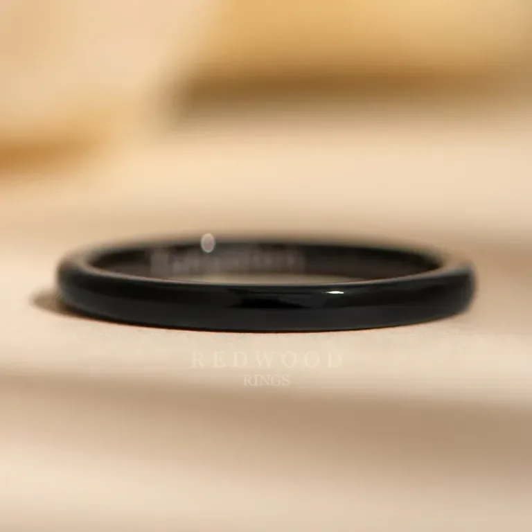 Close-up of a black ring on a beige surface with the words "REDFORD RINGS" faintly visible underneath.