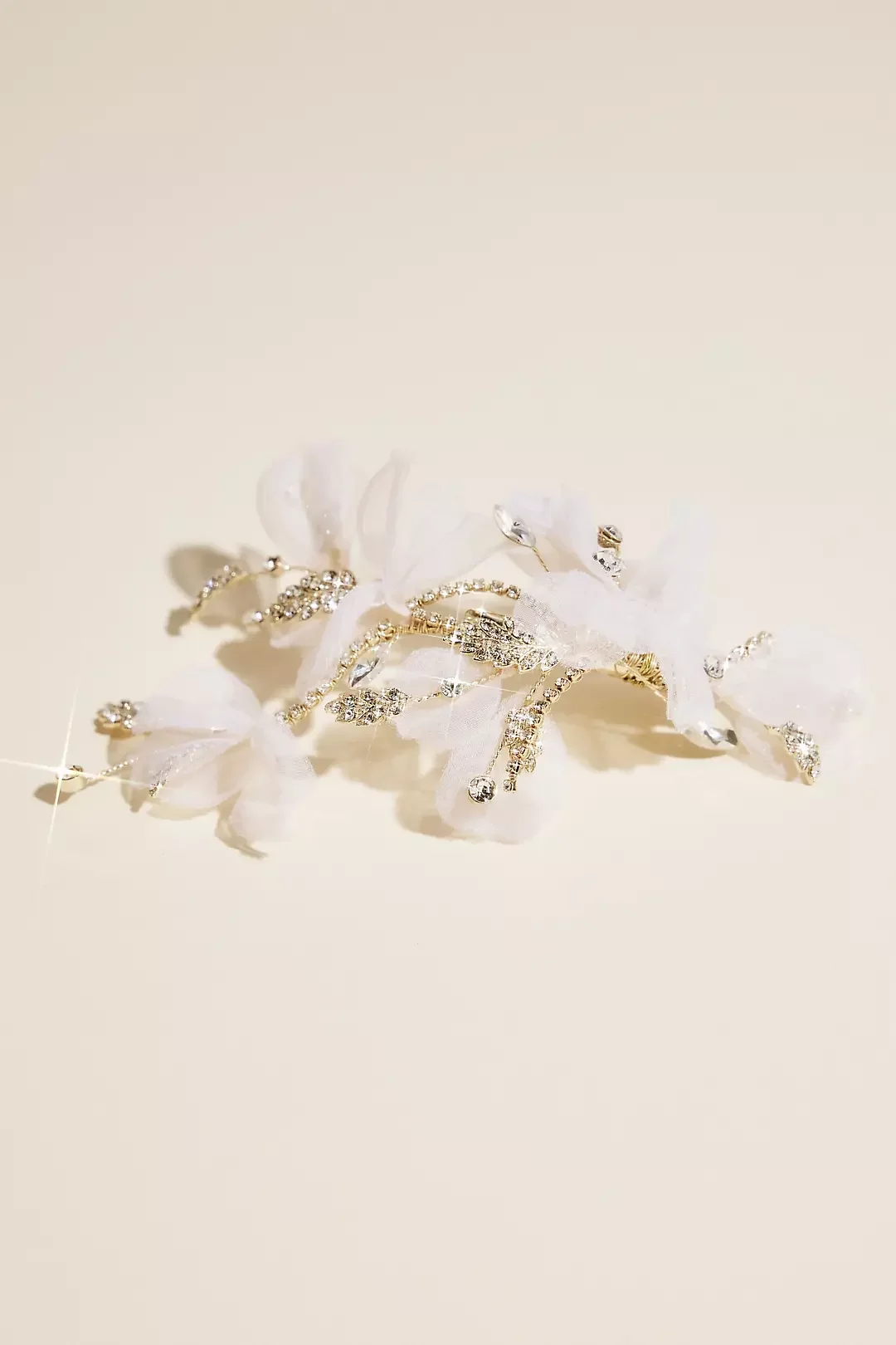 Silver and rhinestone jewelry, possibly a bracelet or hair accessory, on a white surface with fabric and decorative elements.