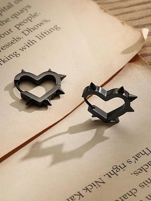 Two black heart-shaped rings with spikes, placed on an open book with yellowed pages.