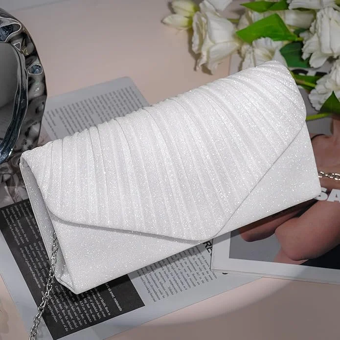 White glittery clutch purse resting on a newspaper, with a bouquet of white flowers in the background.