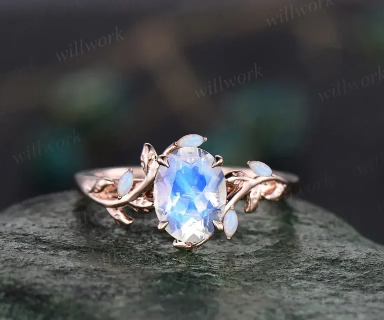 A silver ring with an oval blue gemstone and small opal accents on a textured surface.