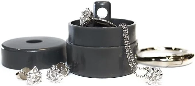 Gray jewelry storage container with diamond earrings, rings, and a chain inside, and additional jewelry pieces outside.