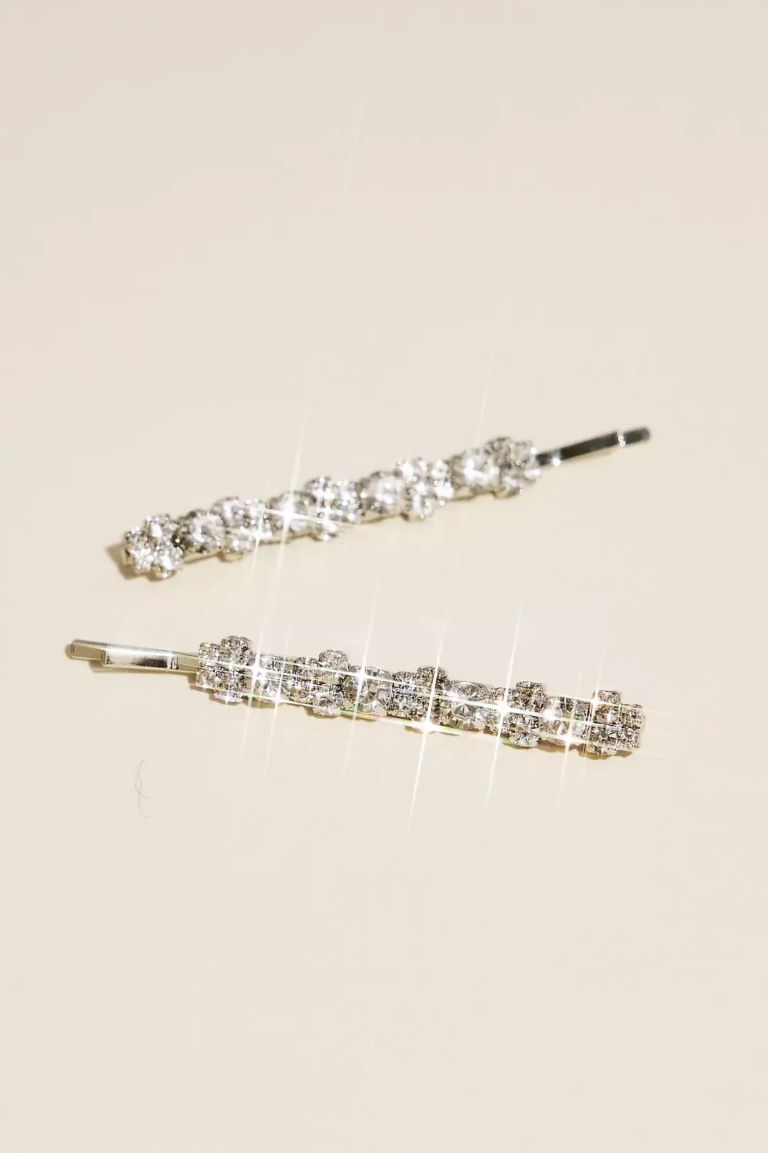 Two decorative hairpins with sparkling rhinestones lay on a light-colored surface.