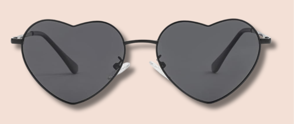 Heart-shaped sunglasses with black frames and dark lenses on a light pink background.