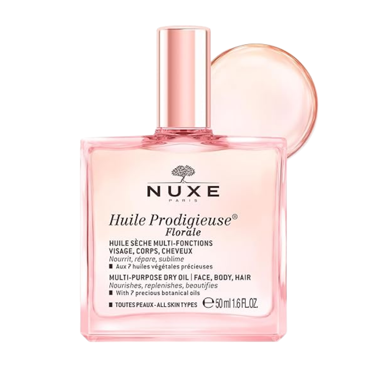 A pink bottle of Nuxe Huile Prodigieuse floral multi-purpose dry oil with a round cap, front label featuring black text and a small tree logo, with a circular splash of the oil behind the bottle.