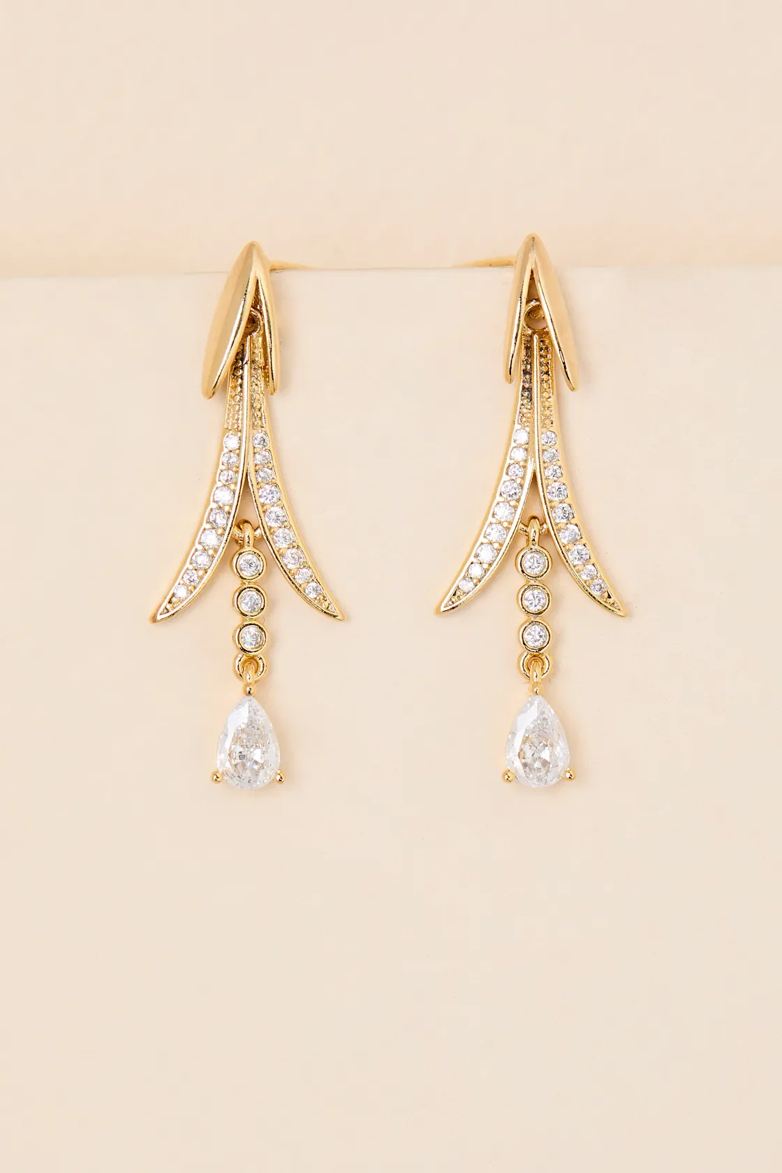 Gold dangling earrings with diamond accents and teardrop-shaped diamonds at the bottom.
