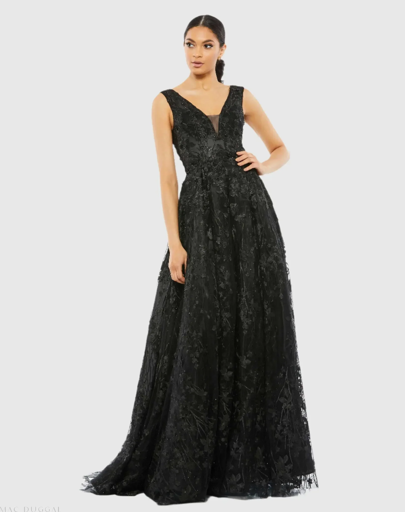 A woman is wearing an elegant, black, floor-length gown with lace and floral embroidery details, featuring a deep V neckline with a sheer black mesh insert.